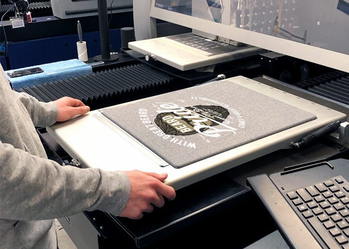 Un t-shirt posé sur le plateau d'une imprimante textile numérique, prêt à être imprimé